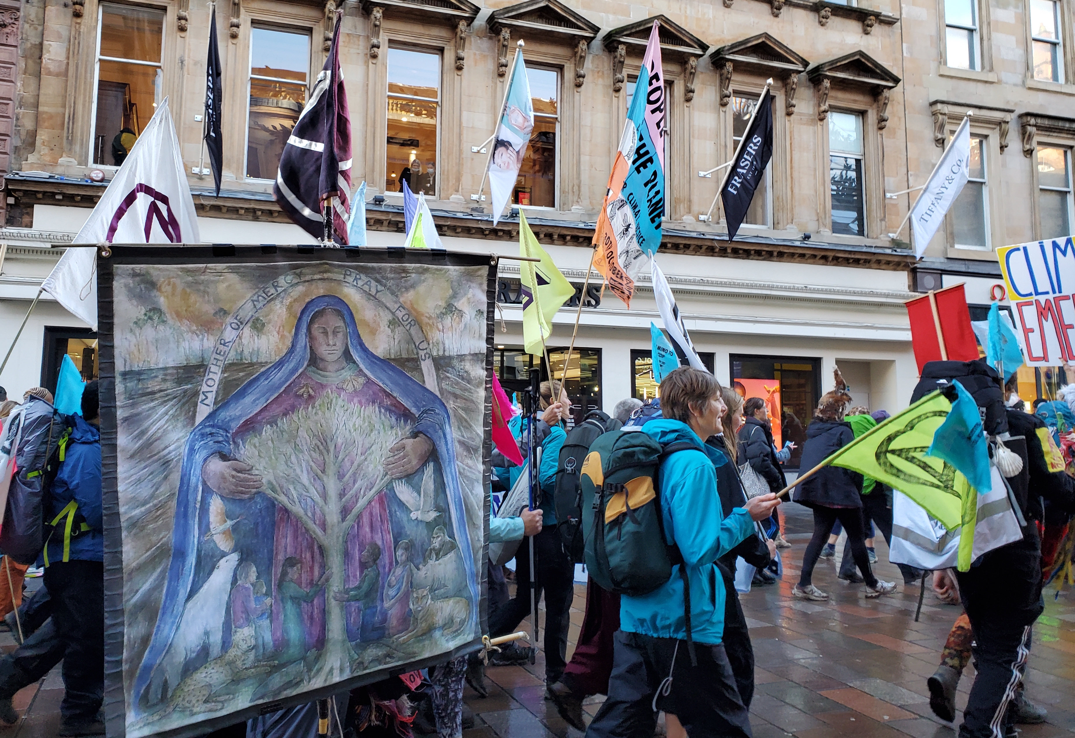 A banner showing Mary embracing a tree is seen in the procession of "climate pilgrims" arriving in Glasgow, Scotland, for the U.N. climate conference known as COP26. (NCR/Brian Roewe) A banner showing Mary embracing a tree is seen in the procession of "climate pilgrims" arriving in Glasgow, Scotland, for the U.N. climate conference known as COP26. (NCR/Brian Roewe)