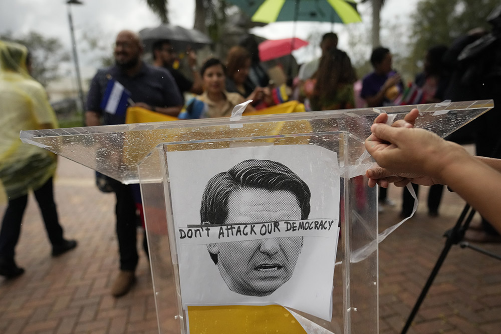 An image of Florida Gov. Ron DeSantis is overlaid with the words "Don't attack our democracy" at a rally to denounce the governor's immigration policies Sept. 20 in Doral, Florida. (AP/Rebecca Blackwell)