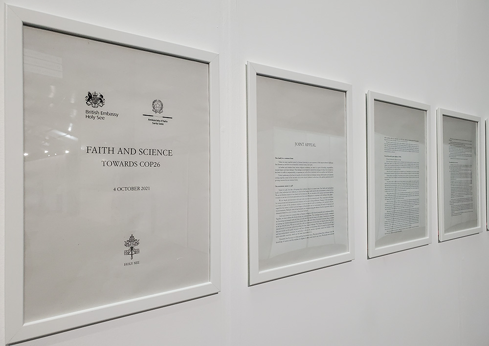 Framed pages of a letter from Pope Francis and nearly 40 other faith leaders, delivered to COP26 leaders on Oct. 4, hang on a wall between the two plenary halls where meetings are taking place. (EarthBeat photo/Brian Roewe)