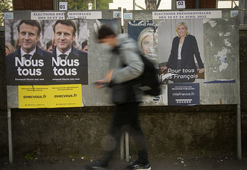 A man walks in front of campaign posters of French President Emmanuel Macron and far-right presidential candidate Marine Le Pen in Sevres, outside Paris, France, April 20. (AP/Christophe Ena)