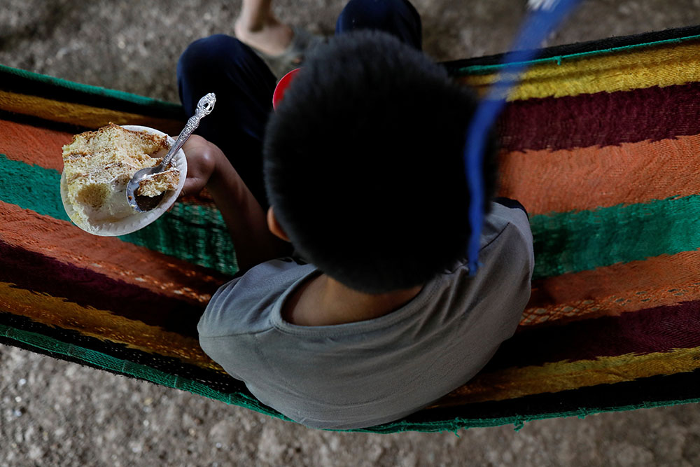 Gustavo, a disabled 12-year-old who was expelled by U.S. authorities and sent back to Guatemala under an emergency health order, holds a piece of cake as part of a welcoming party after being reunited with his father in Peten, Guatemala, Sept. 5. (CNS)