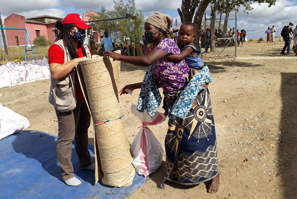 Joseanair Hermes, program manager for Catholic Relief Services in the Cabo Delgado province, at left, distributes relief aid to families displaced by armed conflict in the district of Metuge in the province. (Courtesy of Catholic Relief Services/Caritas/A