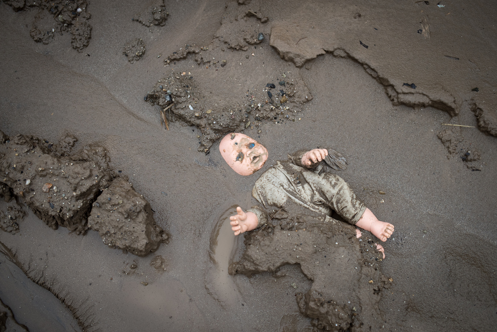 After hurricane Eta and Iota in 2020, a child's doll is stuck in the mud in a street in Chamelecón, San Pedro Sula, Honduras. Scientists say climate change is making storms like those more frequent and more severe. (Photo courtesy of Sean Hawkey, World Co