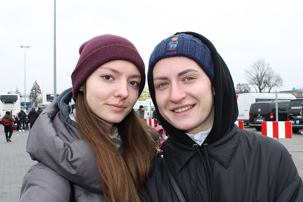 Maryna Zozuliak, right, with her sister, Elisabeth, in the parking lot of a refugee reception center in the southeastern Polish city of Przemyśl. The two were bound for the Netherlands to stay with an aunt living there. (NCR photo/Chris Herlinger)