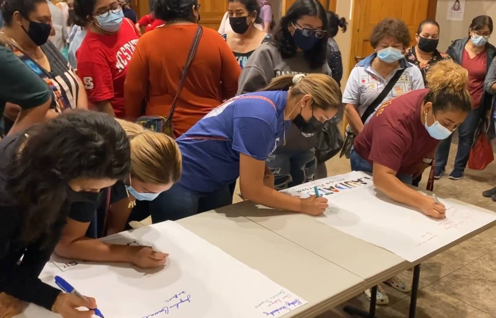 Parishioners of Immaculate Conception Catholic Church, in Durham, North Carolina, sign pledge sheets committing the parish the joining the Vatican's Laudato Si' Action Platform during a December event. (NCR screenshot)