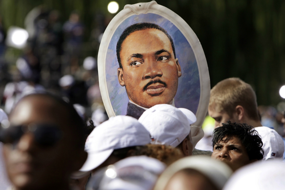 A woman holds a portrait of the Rev. Martin Luther King Jr. during the 2011 dedication of the King memorial at the National Mall in Washington. (CNS/Reuters/Yuri Gripas) 