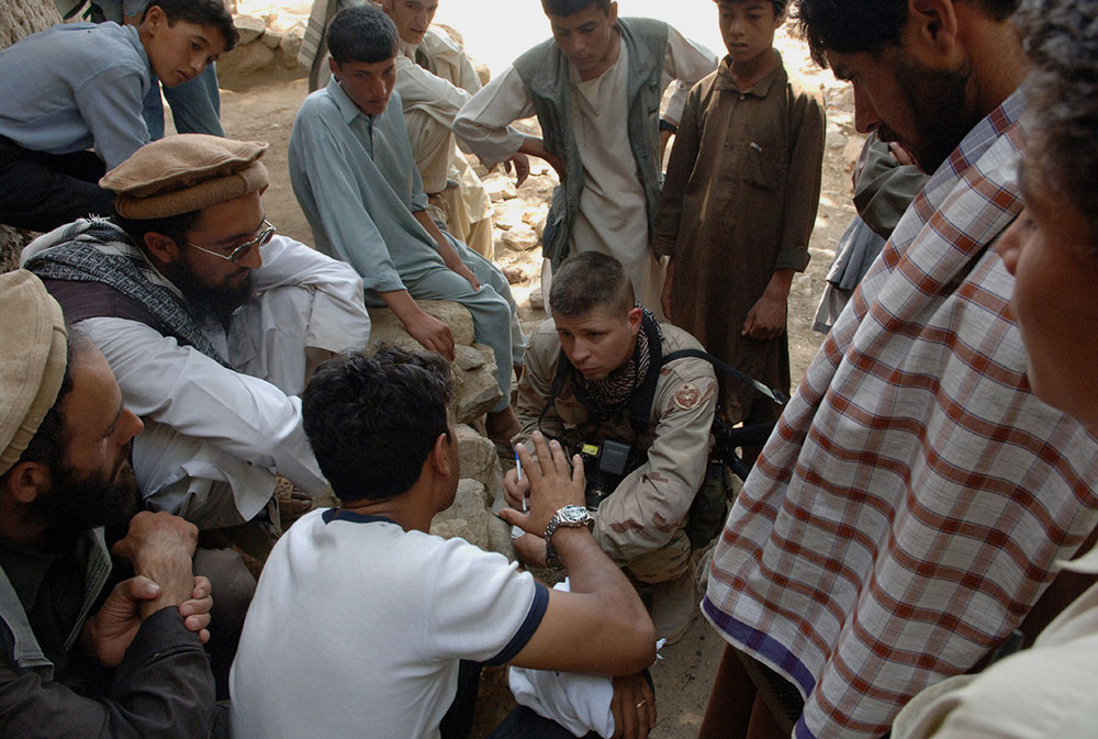 Sgt. Matthew MacRoberts, center, of Task Force Eagle, interviews the local mullah in the village of Qual-A-Atakhom, Afghanistan. Task Force Eagle conducted medical civilian assistance procedures in the village on Aug. 16, 2005. (U.S. Army/SPC Joshua Balog
