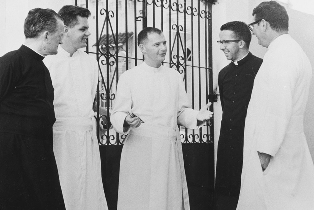 In 1966, Msgr. Theodore McCarrick (center), president of the Catholic University of Puerto Rico, chats with staff of the Inter-American Center, where clerics and laypeople were trained for service in Latin America. From left: Fr. James McNiff, Fr. John Ri