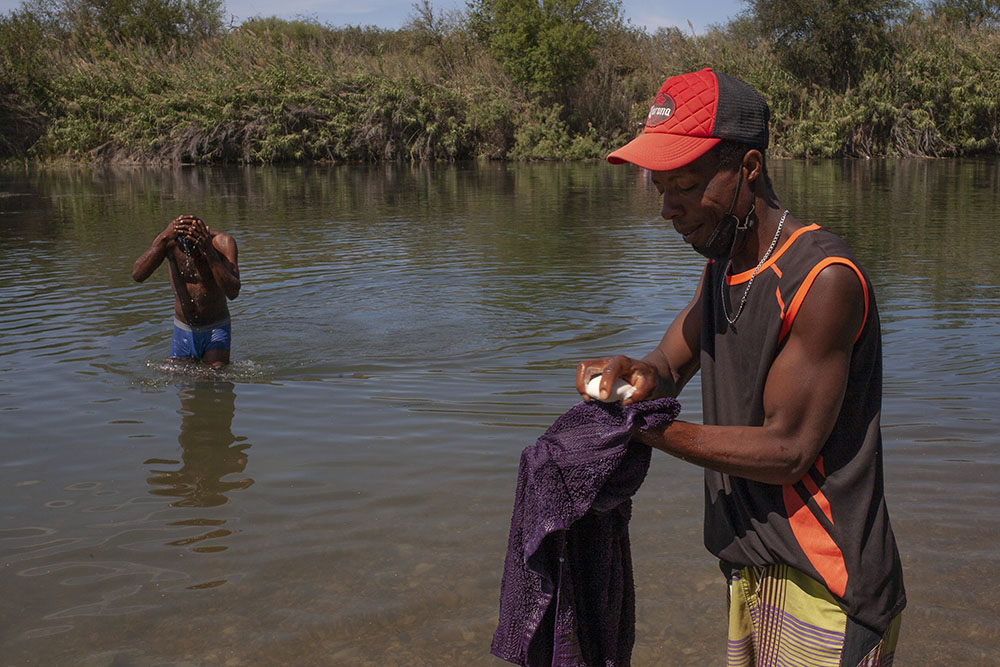 Haitian immigrants Mike Jean Louis, left, and Vilconet Jean Batiste bathe and wash clothes in the Rio Grande at a camp in Ciudad Acuña, Mexico, Sept. 22. Jean Batiste said he wants to remain in Mexico. (Nuri Vallbona)