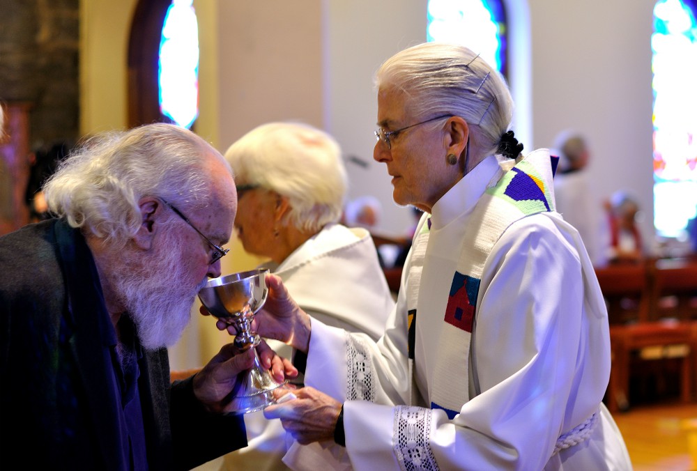 Emily Hewitt serves Communion to Jonathan Cheek at a memorial service for his mother, Alison Cheek, on Nov. 2 at St. Philip’s Episcopal Church in Brevard, North Carolina. (Darlene O’Dell)