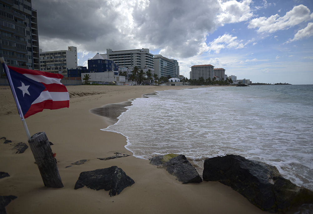 A Puerto Rican flag flies on an empty beach at Condado Beach May 21, 2020, in San Juan, Puerto Rico. (AP/Carlos Giusti, File)
