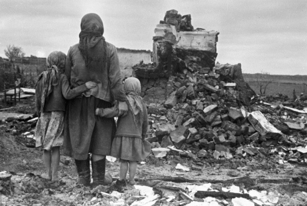 A woman and two girls look at their destroyed house during World War II in Russia in the Soviet Union, Sept. 1, 1943. (Wikimedia Commons/RIA Novosti archive, image #982/S. Alperin/CC-BY-SA 3.0)