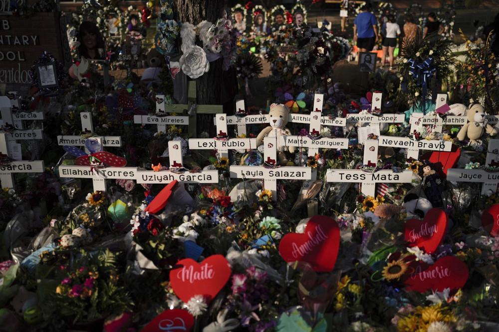 Flowers are piled around crosses with the names of the victims killed in a school shooting as people visit a memorial at Robb Elementary School to pay their respects May 31 in Uvalde, Texas. (AP/Jae C. Hong)