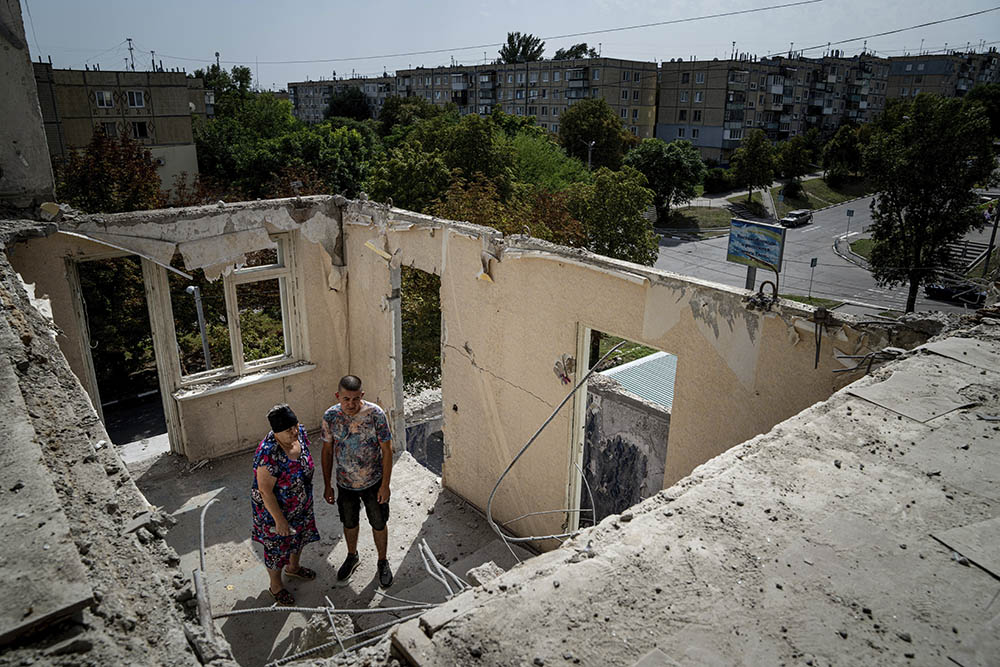 Widow Liudmyla Shyshkina, 74, and her son Pavlo Shyshkin, 46, stand at their apartment house, which was destroyed after Russian bombardment of residential area in Nikopol, Ukraine, Aug, 22. (AP/Evgeniy Maloletka)