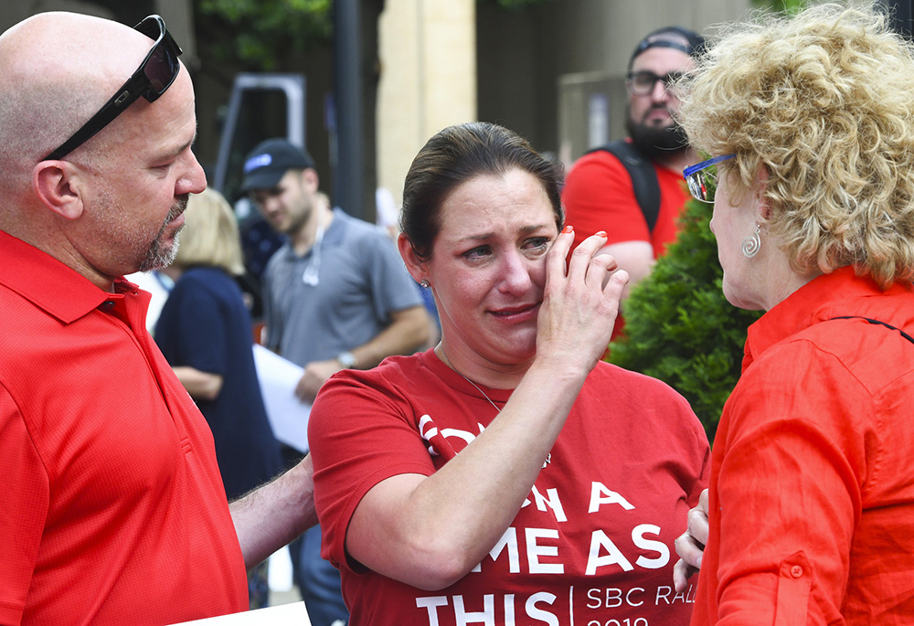 In this June 11, 2019 file photo, Jules Woodson, center is comforted by her boyfriend Ben Smith, left, and Christa Brown during a demonstration outside the Southern Baptist Convention's annual meeting in Birmingham, Alabama. (AP photo/Julie Bennett, file)