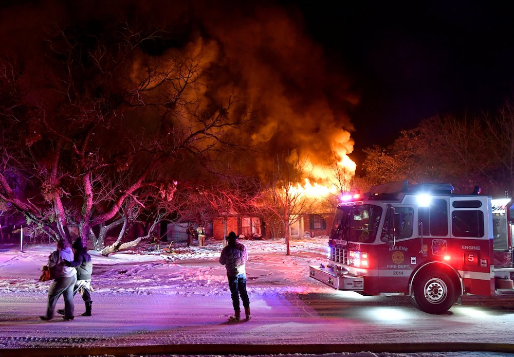 Residents in Abilene, Texas, walk past their burning house Feb. 15. Firefighters were only able to draw water from one hydrant because because cold-weather power outages affected water treatment plants. (CNS photo/Ronald W. Erdrich, Reporter-News, USA Tod