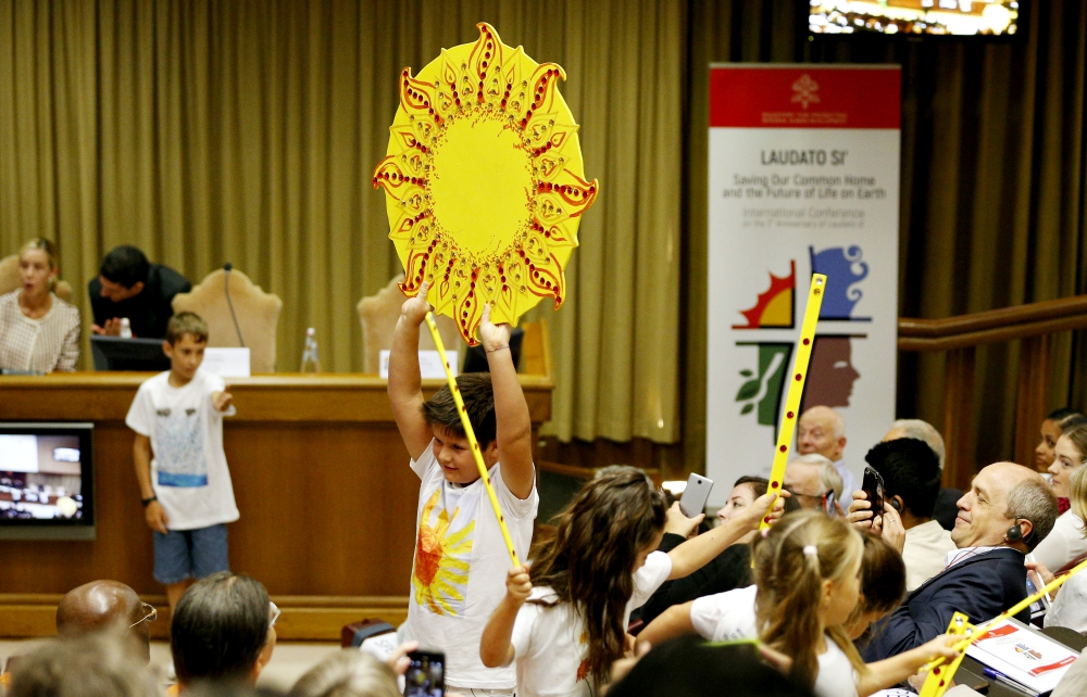 A boy holds up artwork of the sun as children perform at the start of an international conference marking the third anniversary of Pope Francis' encyclical "Laudato Si', on Care for Our Common Home" at the Vatican July 5, 2018. (CNS/Paul Haring)