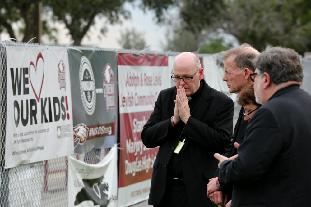 On June 14, 2018, outside Marjory Stoneman Douglas High School in Parkland, Florida, representatives of the U.S. Conference of Catholic Bishops pray for the victims of a shooting at the school in February of that year. (CNS/Bob Roller)