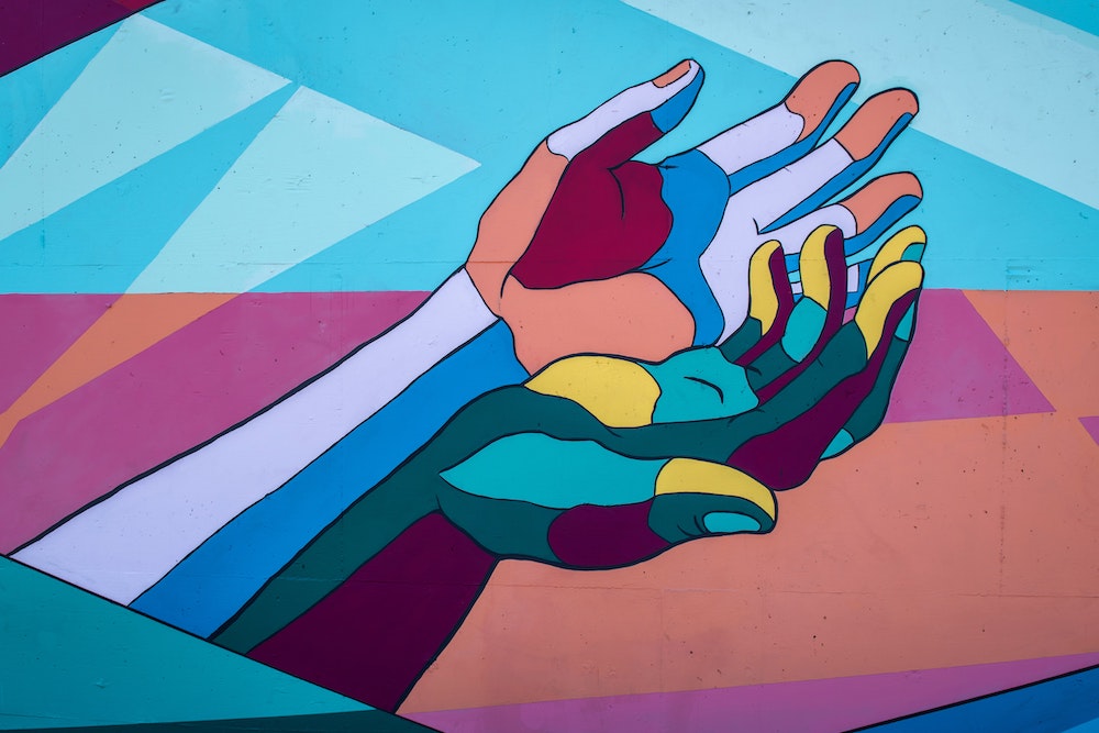 Photo of a mural of multicolored hands (Unsplash/Tim Mossholder)