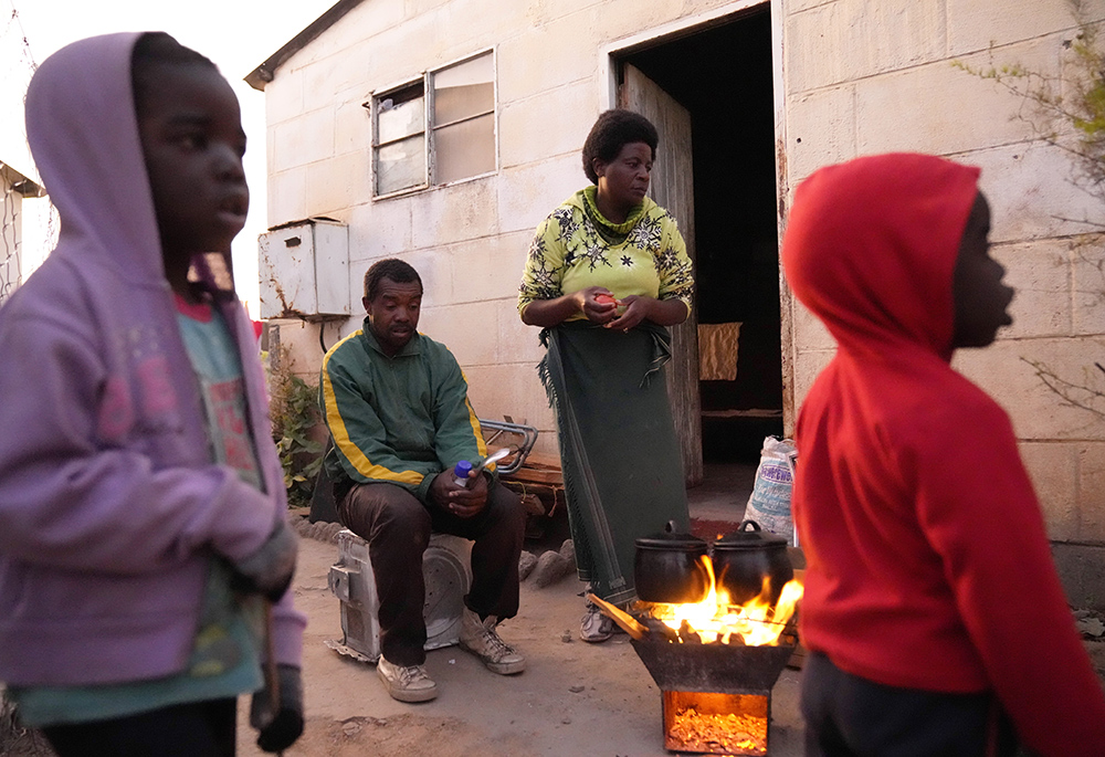 Jeffrey Carlos, center, sits outside his house with his family Aug. 3 on the outskirts of Harare, Zimbabwe. (AP photo/Tsvangirayi Mukwazhi)