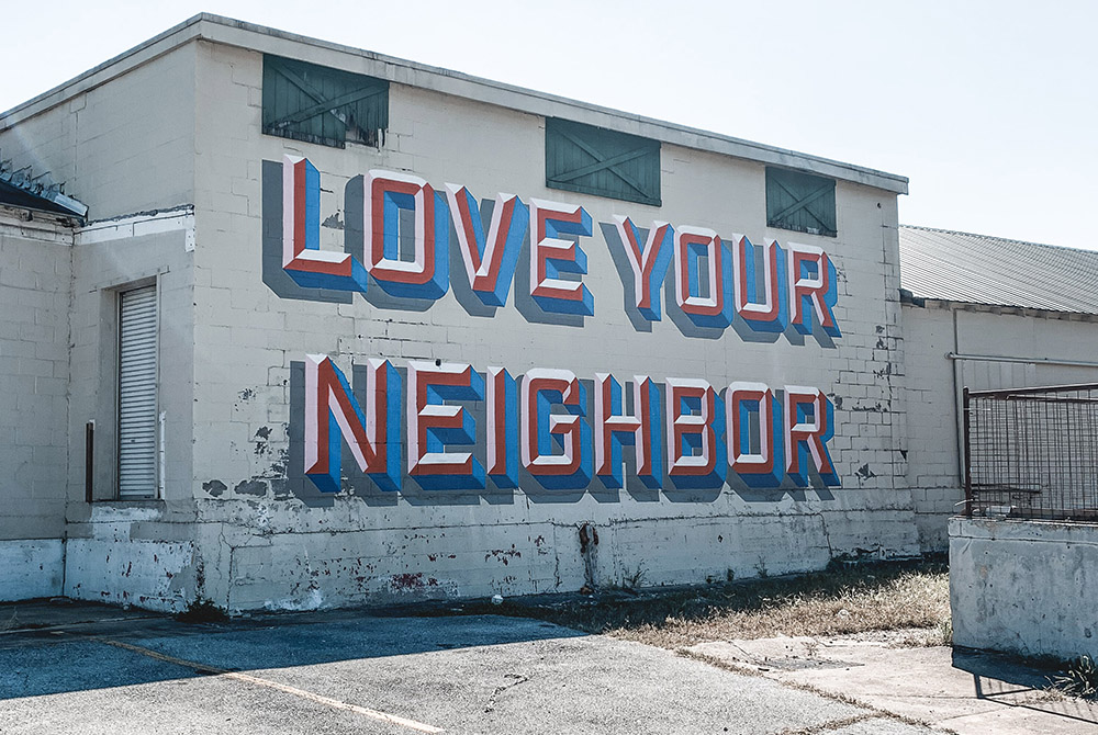 Photo illustration of graffiti that reads "Love Your Neighbor" (Unsplash/Derick McKinney)