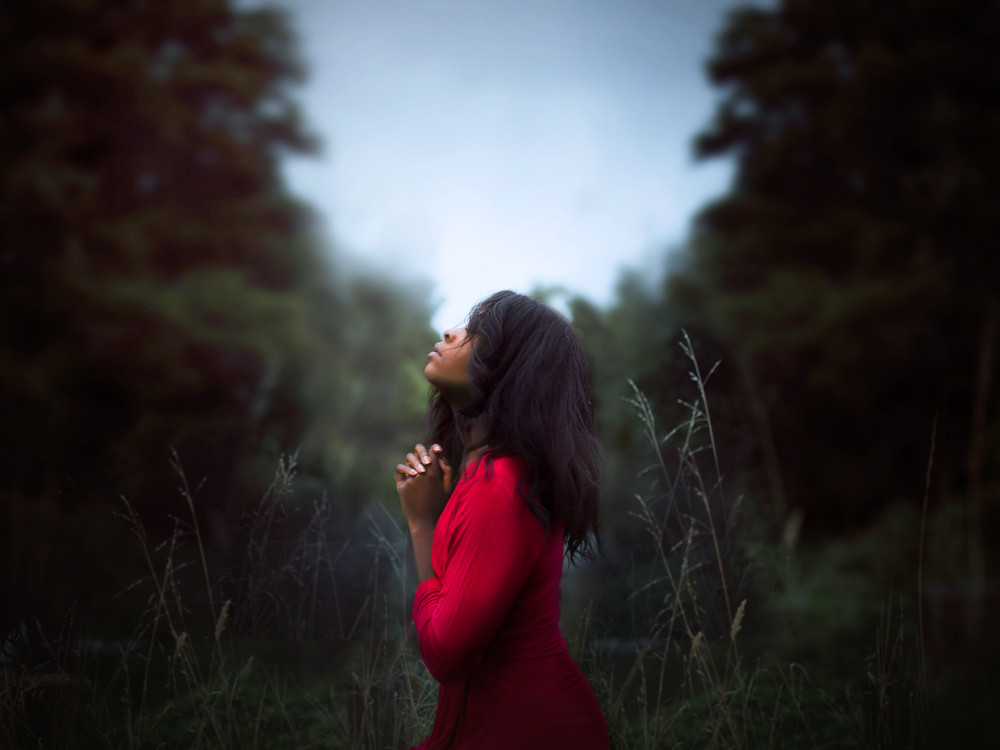 A person prays at a nature preserve in Auckland, New Zealand. (Unsplash/Diana Simumpande)