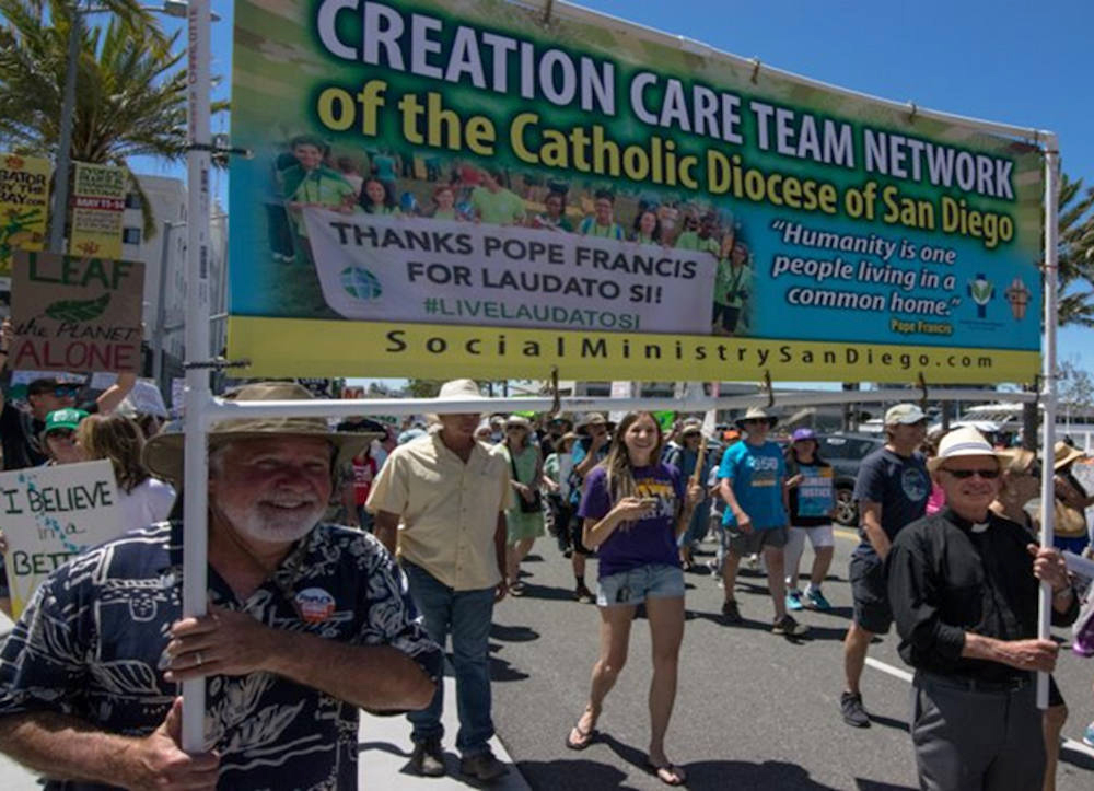 Fr. Emmet Farrell, right, carries a banner for the Diocese of San Diego's creation care team network during a climate march in March 2017. (Provided photo)