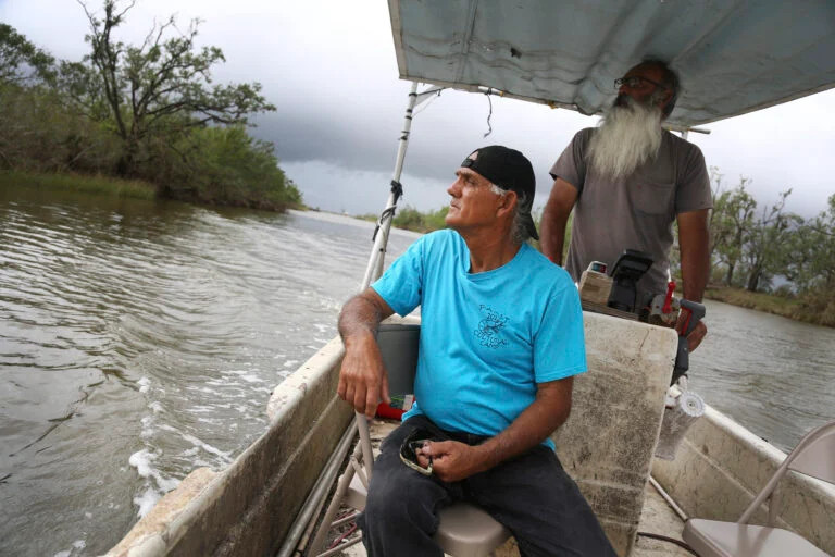 Donald Dardar, left, and Russell Dardar look toward the eroding shoreline of Bayou Pointe-au-Chien in southern Louisiana on Wednesday, Sept. 29, 2021. (AP/Jessie Wardarski)