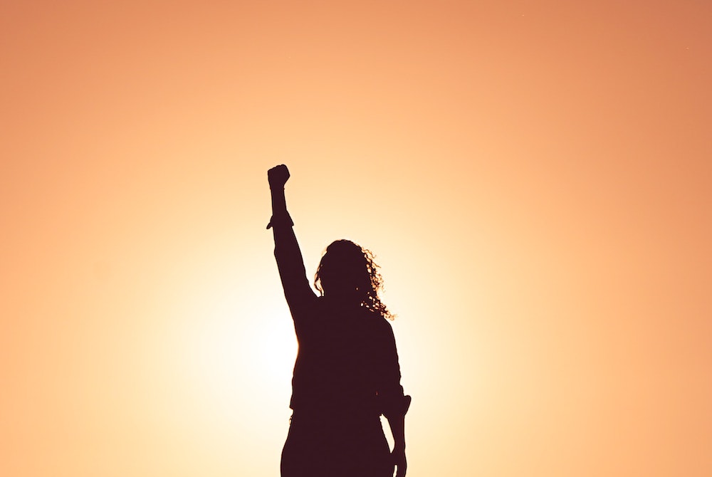 silhouette of person with long hair and fist raised