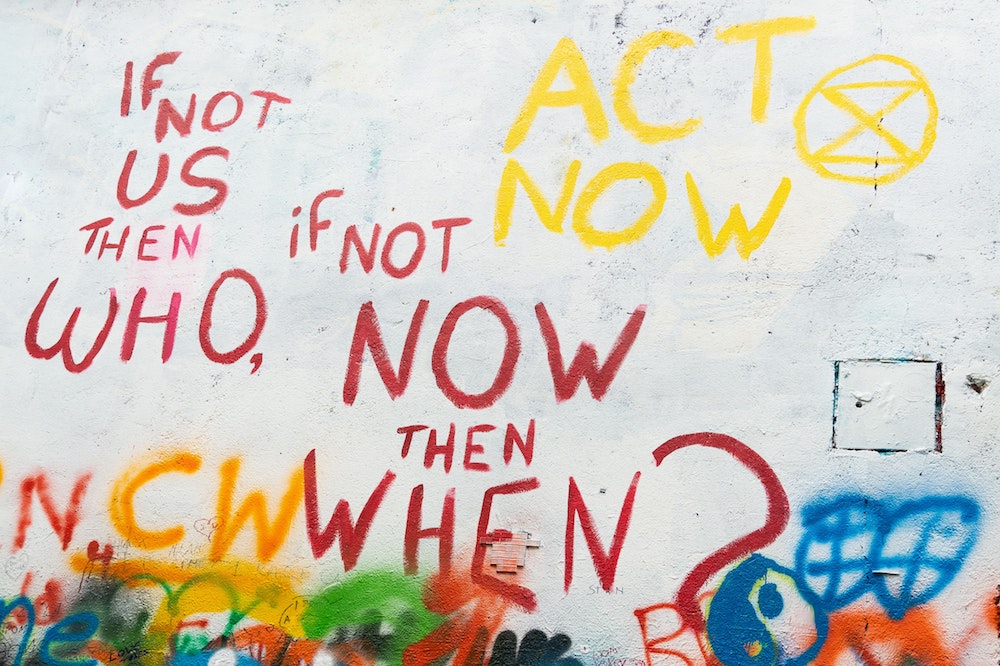 Wall painting that says "If not us, then who, if not now, then when?" (Unsplash/Rod Long)