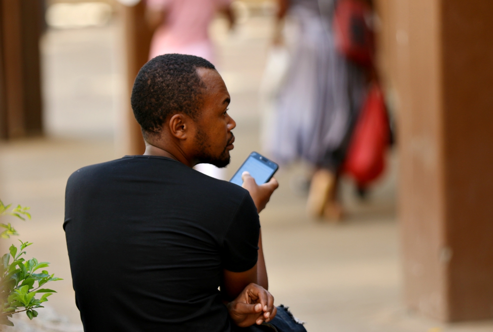 A man checks his mobile phone in Harare, Zimbabwe, in January. (Newscom/Reuters/Philimon Bulawayo)