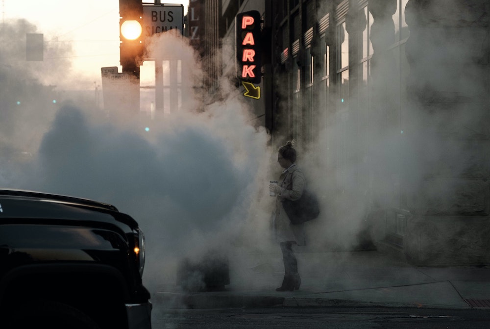 woman on street obscured by car exhaust