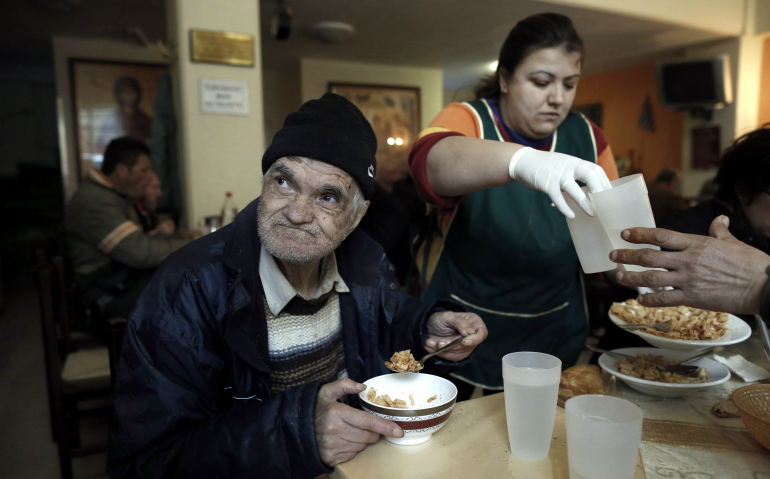 A homeless man eats his meal in 2015 at a soup kitchen run by the Archdiocese of Athens in Greece. Europe's top Catholic charitable agency has published a "road map for social justice and equality," urging all church members to defend the poor and marginalized. (CNS photo/Yannis Kolesidis, EPA)