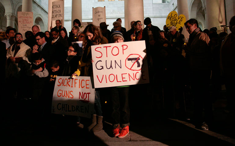 Nine-year-old Sophie Bell, center, holds a sign during an interfaith prayer vigil to end gun violence Dec. 19 in front of Los Angeles City Hall. (CNS/Reuters/Jason Redmond