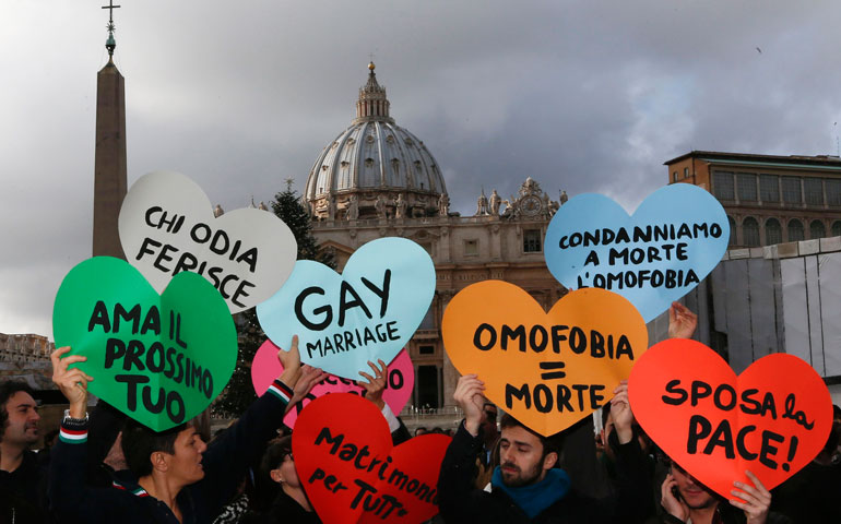 Members of a gay activist group hold up signs outside St. Peter’s Square at the Vatican Dec. 16. (CNS/Reuters/Alessandro Bianchia)