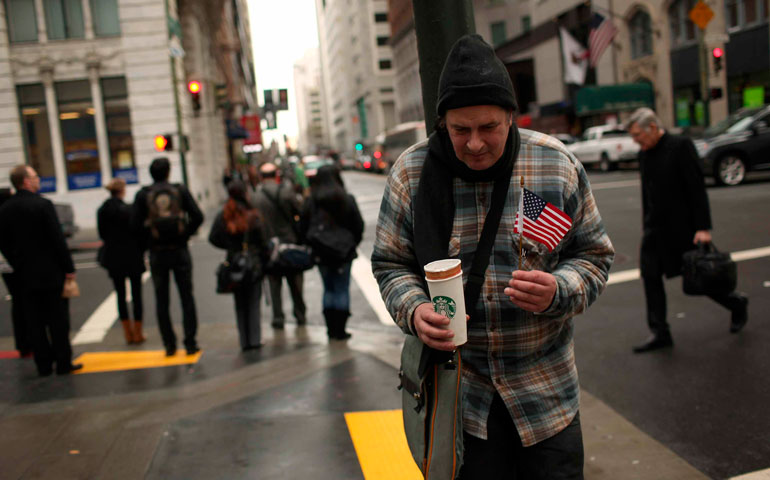 A man who is panhandling holds an American flag in the financial district in San Francisco March 28, 2012. (CNS/Reuters/Robert Galbraith)