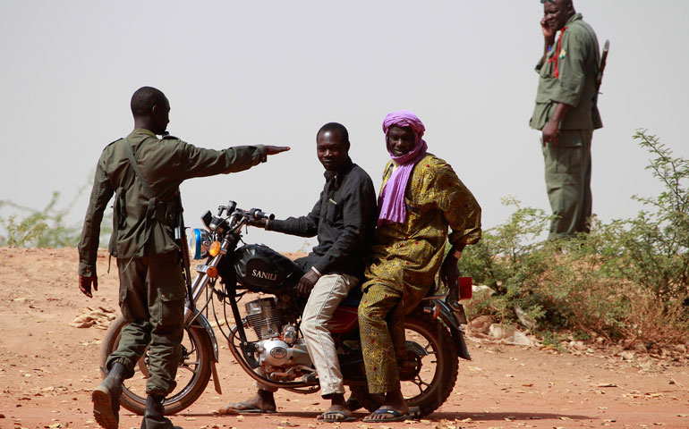 A Malian soldier checks two civilians riding on a motorcycle Jan. 24 in Diabaly, which was recently liberated by French and Malian forces from Islamic rebels. (CNS/Reuters/Eric Gaillard)