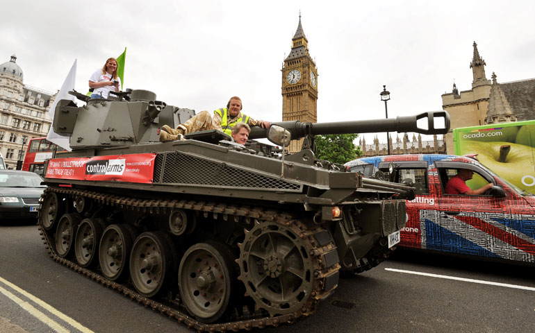 Activists in a tank with a banner attached to the side supporting the Arms Trade Treaty drive through Parliament Square in central London June 27. (Associated Press/John Stillwell)