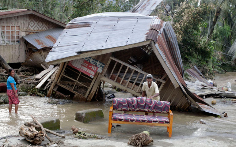 A man cleans his sofa outside of his destroyed house after Typhoon Bopha hit Compostela Valley, southern Philippines, Dec. 5. (CNS/Reuters/Erik De Castro)