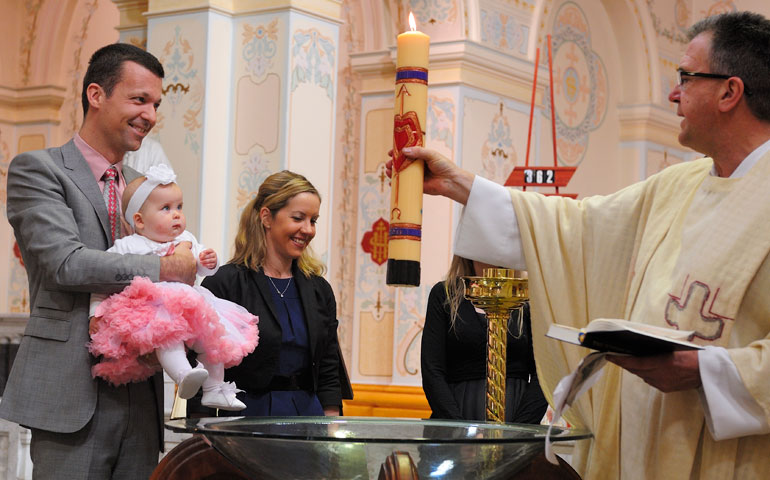 Fr. John Petrulis, right, leads the baptism of a young Catholic at Sacred Heart Parish in Melbourne, Australia. (Maria George)