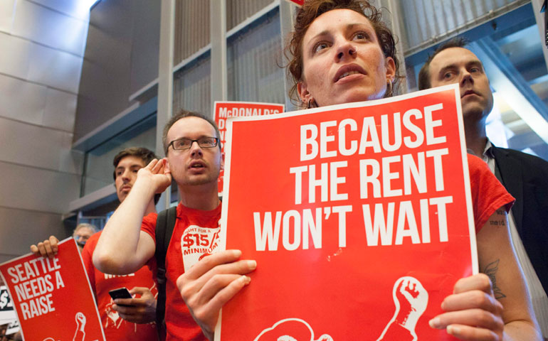 Labor activists hold signs during a Seattle City Council meeting in which the council voted on raising the minimum wage to $15 per hour on June 2, 2014. (CNS/Reuters/Davis Ryder)
