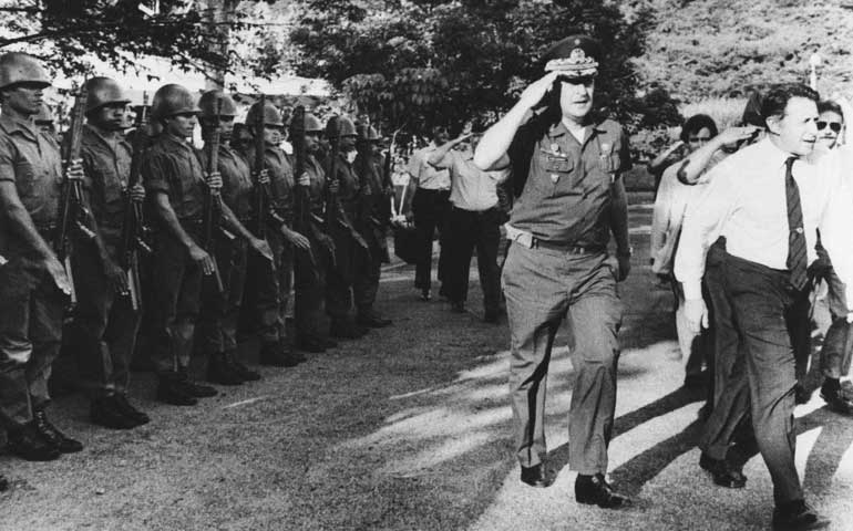 U.S. Secretary of Defense Caspar Weinberger, right, walks with Gen. Carlos Eugenio Vides Casanova in front of Salvadoran troops in San Juan Opica, El Salvador, on Sept. 7, 1983. (AP Photo/Romero)