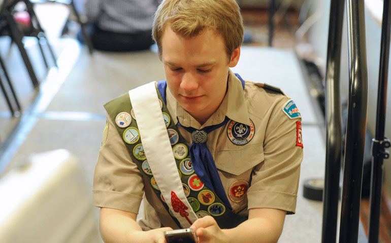 Pascal Tessier, 16, who was facing expulsion from the Boy Scouts because he is gay, sends out a text message after a resolution to allow openly gay Scouts was passed May 23. (CNS/Reuters/Michael Prengler)