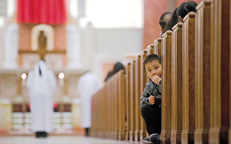 A young boy looks out from a pew during Good Friday prayers April 3 at St. Helena Catholic Church in Philadelphia. (AP Photo/Matt Rourke)