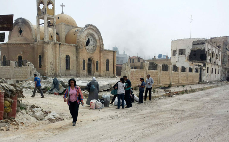 Residents walk near a damaged church June 8 in Qusair, Syria, on their way to inspect their houses and collect their belongings. (CNS/Reuters/Rami Bleibel)