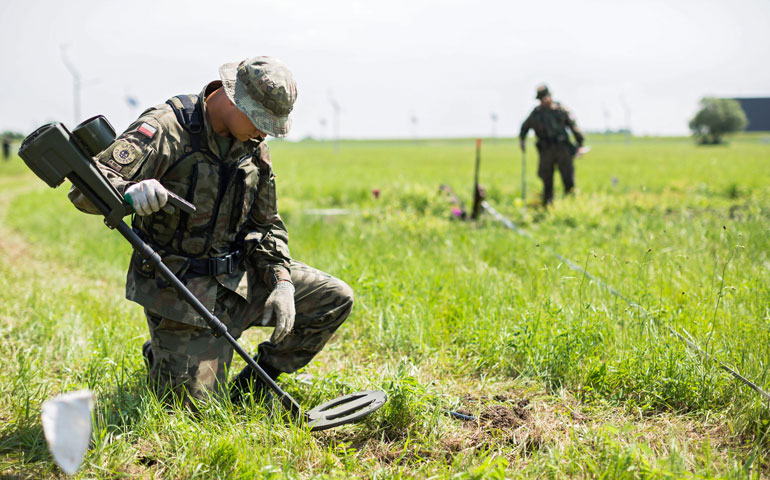 Members of Poland's 6th Airborne Brigade based in Krakow, Poland, search an area with metal detectors July 1 where the main celebrations of the World Youth Days will be held near Wieliczka. (CNS/EPA/Stanslaw)