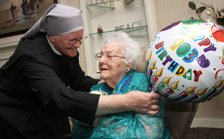 Sr. Elizabeth Anne Roche adjusts a balloon next to honoree Rita Driess forf centenarians Jan. 20 at the Little Sisters of the Poor’s Queen of Peace Residence in the Queens borough of New York. (CNS/Gregory A. Schemitz)