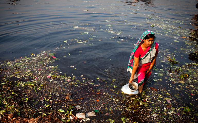 A woman collects dirty water, to be put over produce at a vegetable market, from the polluted Buriganga River in Dhaka, Bangladesh, March 19. A large swathe of the river has turned pitch-black with toxic waste, oil and chemicals flowing into it from industrial units. (Newscom/ZUMA Press/KM Asad)