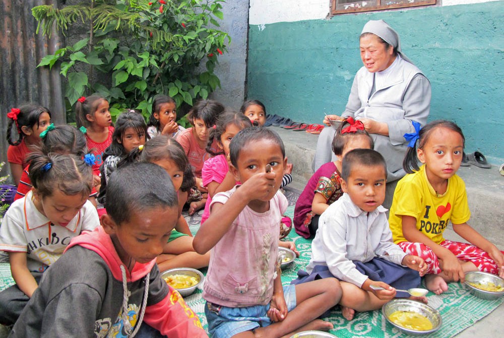 Sr. Martha Park Byongsuk enjoys a midday meal with the children at St. Paul’s Happy Home in Pokhara's Bus-Park slum in Nepal. (Provided photo)