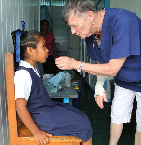 Mercy Sr. Mary McGrory, a registered nurse and psychologist from the Brooklyn, N.Y., diocese, gives a schoolgirl medicine March 16 at a clinic in the village of Wakapoa along the Pomeroon River in Guyana. (CNS/Bob Roller)